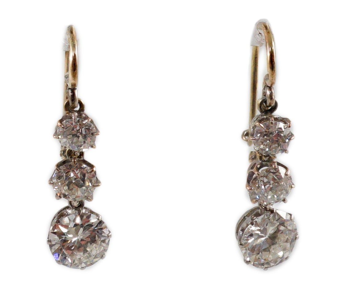 A pair of early to mid 20th century gold, platinum and graduated three stone diamond set drop earrings
